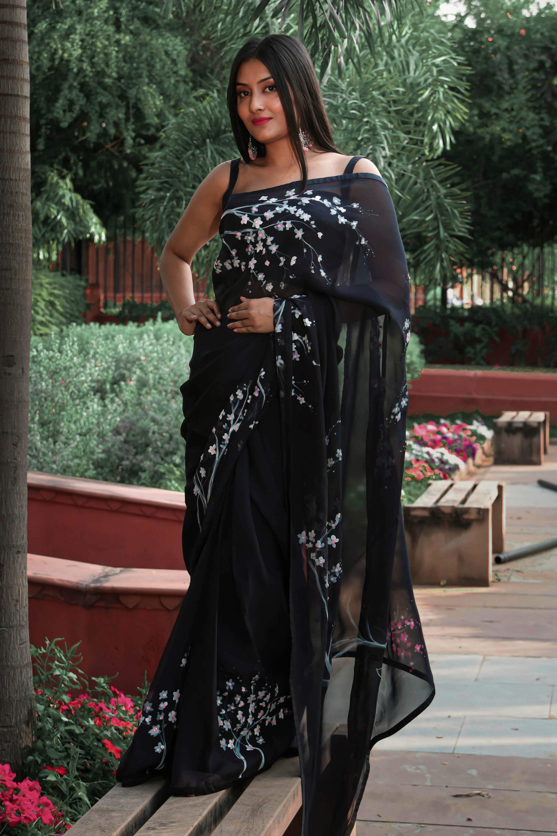 Elegant black organza saree with hand-painted floral design, perfect for parties and special occasions. Features a stunning black saree blouse design and intricate hand painting on saree. This organza saree offers a chic and stylish look, ideal for women who appreciate black saree in silk. A fashionable choice for black saree party wear