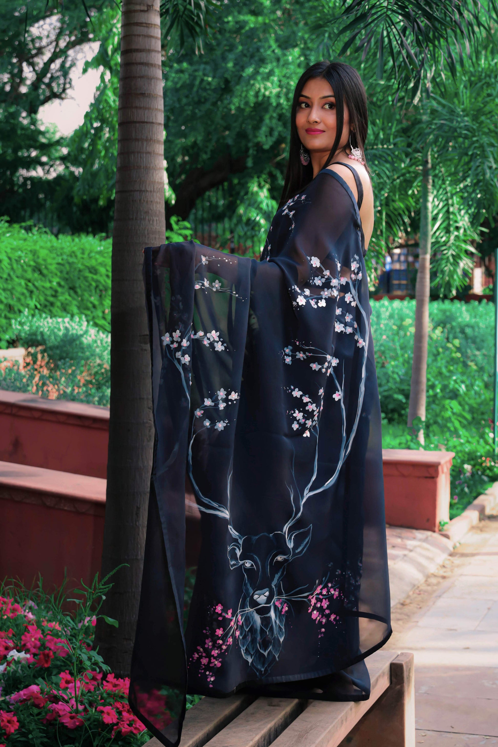 Elegant black organza saree with hand-painted floral design, perfect for parties and special occasions. Features a stunning black saree blouse design and intricate hand painting on saree. This organza saree offers a chic and stylish look, ideal for women who appreciate black saree in silk. A fashionable choice for black saree party wear