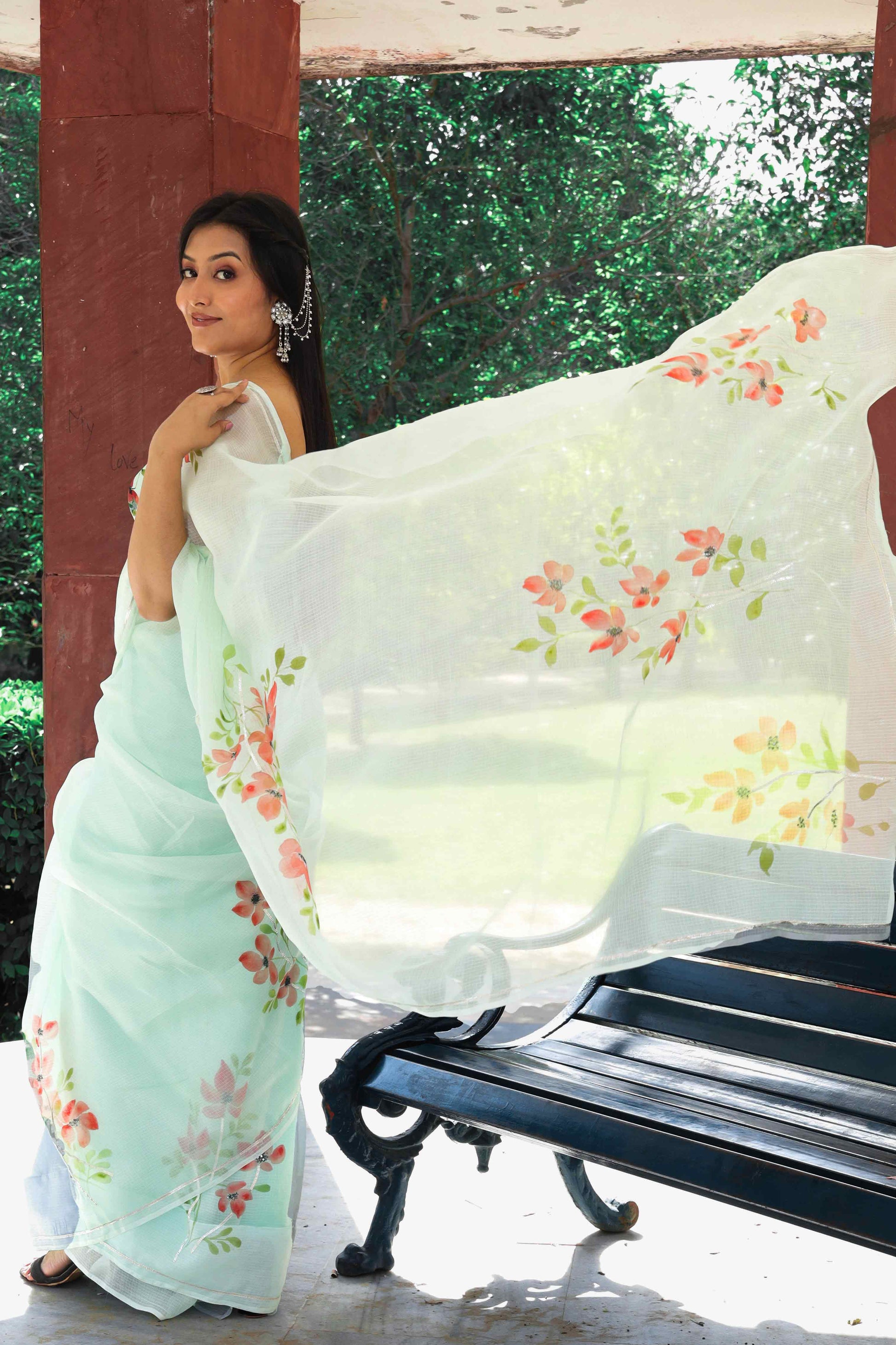 A stunning green Kota Doria saree adorned with hand-painted red flowers and embellished with sequins and gota embroidery. Perfect for silk saree blouse designs, hot saree styles, and the latest saree blouse designs in 2022. Ideal for saree enthusiasts looking for a simple yet elegant look. This hand-painted saree is a work of art, making it a great choice for engagement and party looks. Explore the best saree shop near you for this pure Kota silk masterpiece
