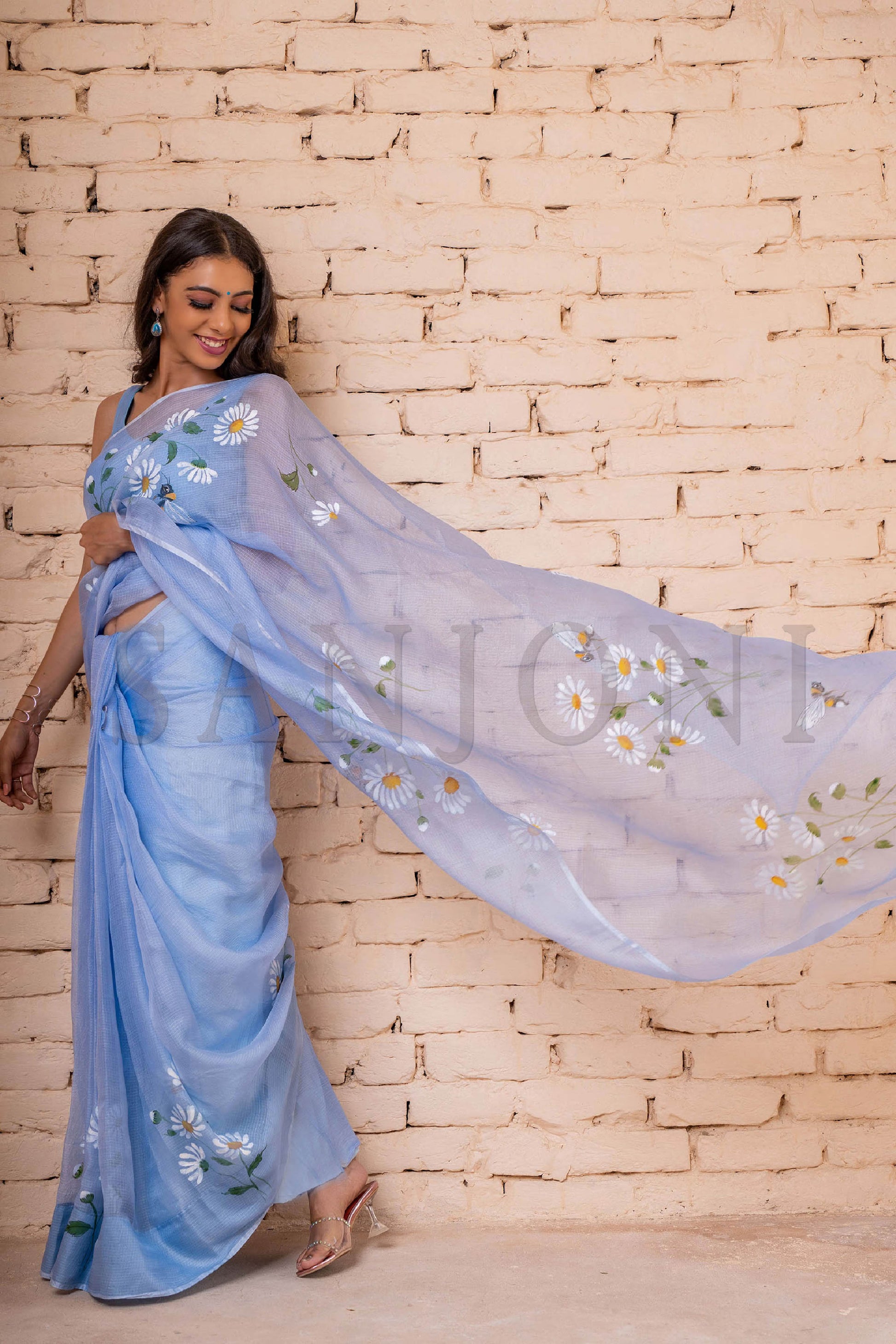 Exquisite hand-painted Kota Doria Silk Saree adorned with delicate white daisies, intricately enhanced with sequin and gota hand embroidery. A masterpiece of hand painting on saree, showcasing the elegance of pure Kota silk. This Kota saree is a timeless beauty that epitomizes artistry and grace.