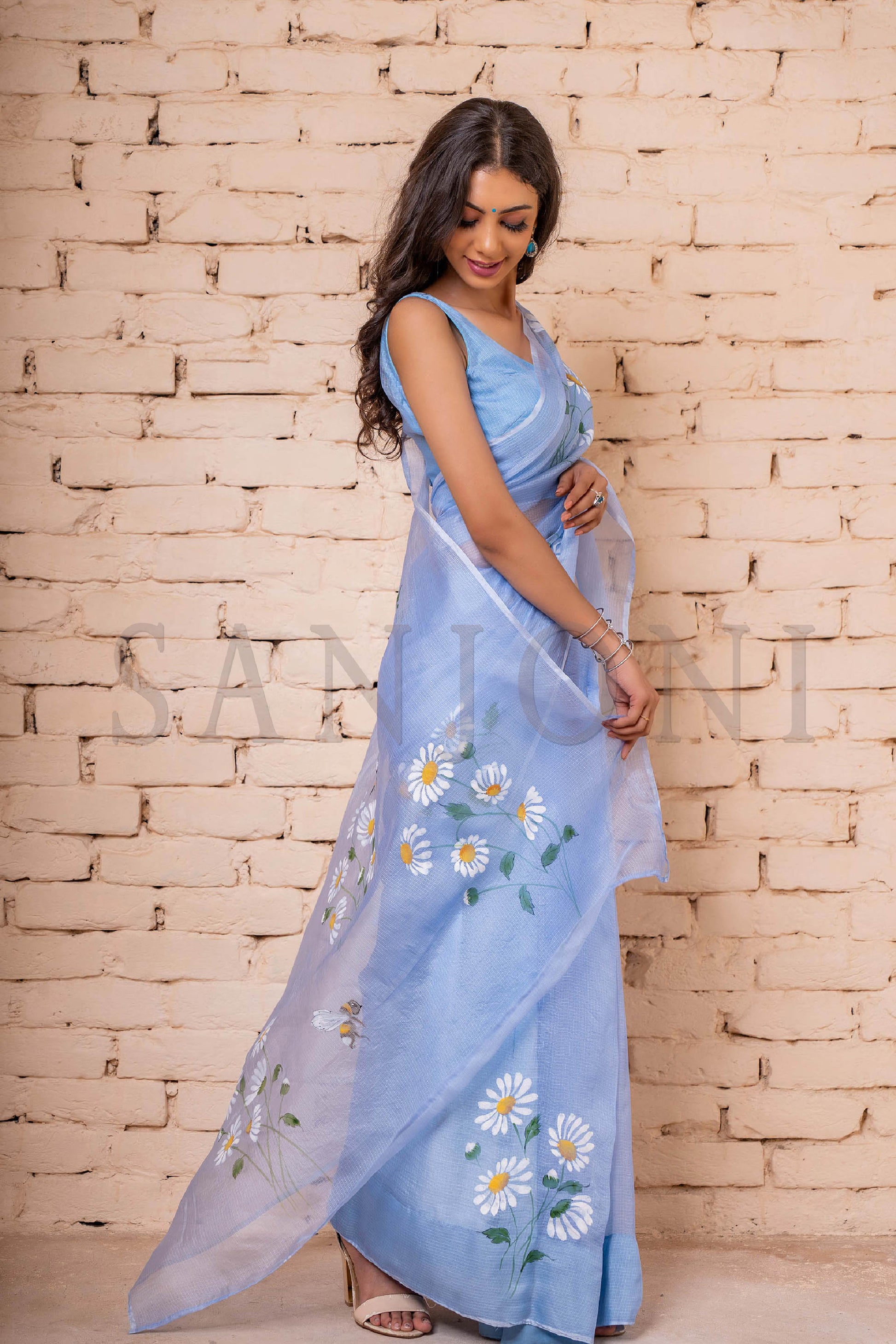 Exquisite hand-painted Kota Doria Silk Saree adorned with delicate white daisies, intricately enhanced with sequin and gota hand embroidery. A masterpiece of hand painting on saree, showcasing the elegance of pure Kota silk. This Kota saree is a timeless beauty that epitomizes artistry and grace.