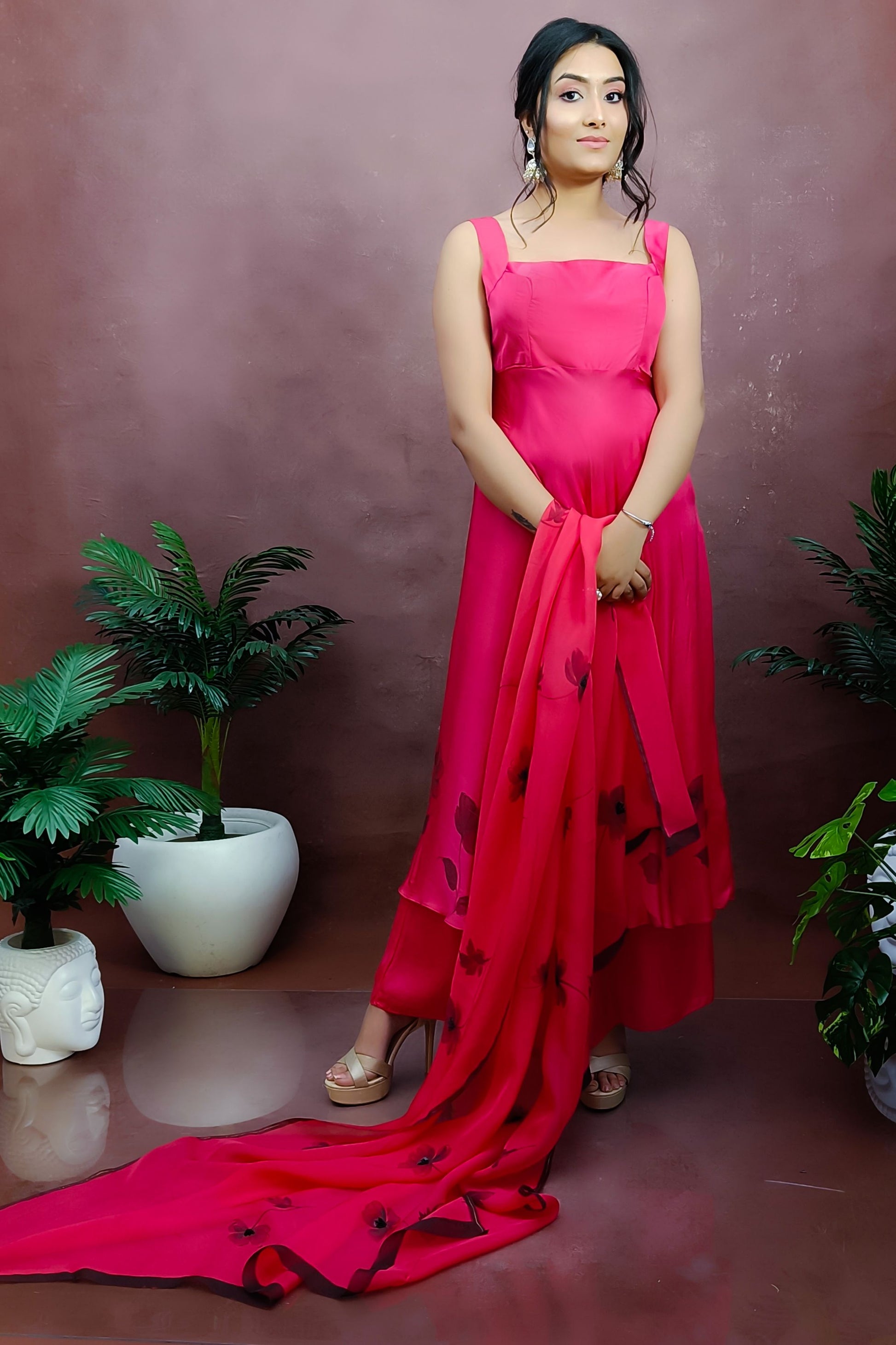 Girl wearing a red colour sleeveless anarkali suit enhanced with hand painted black poppy flowers adorned with delicate bead work., paired with organza handpainted dupatta and a flared palazzo.