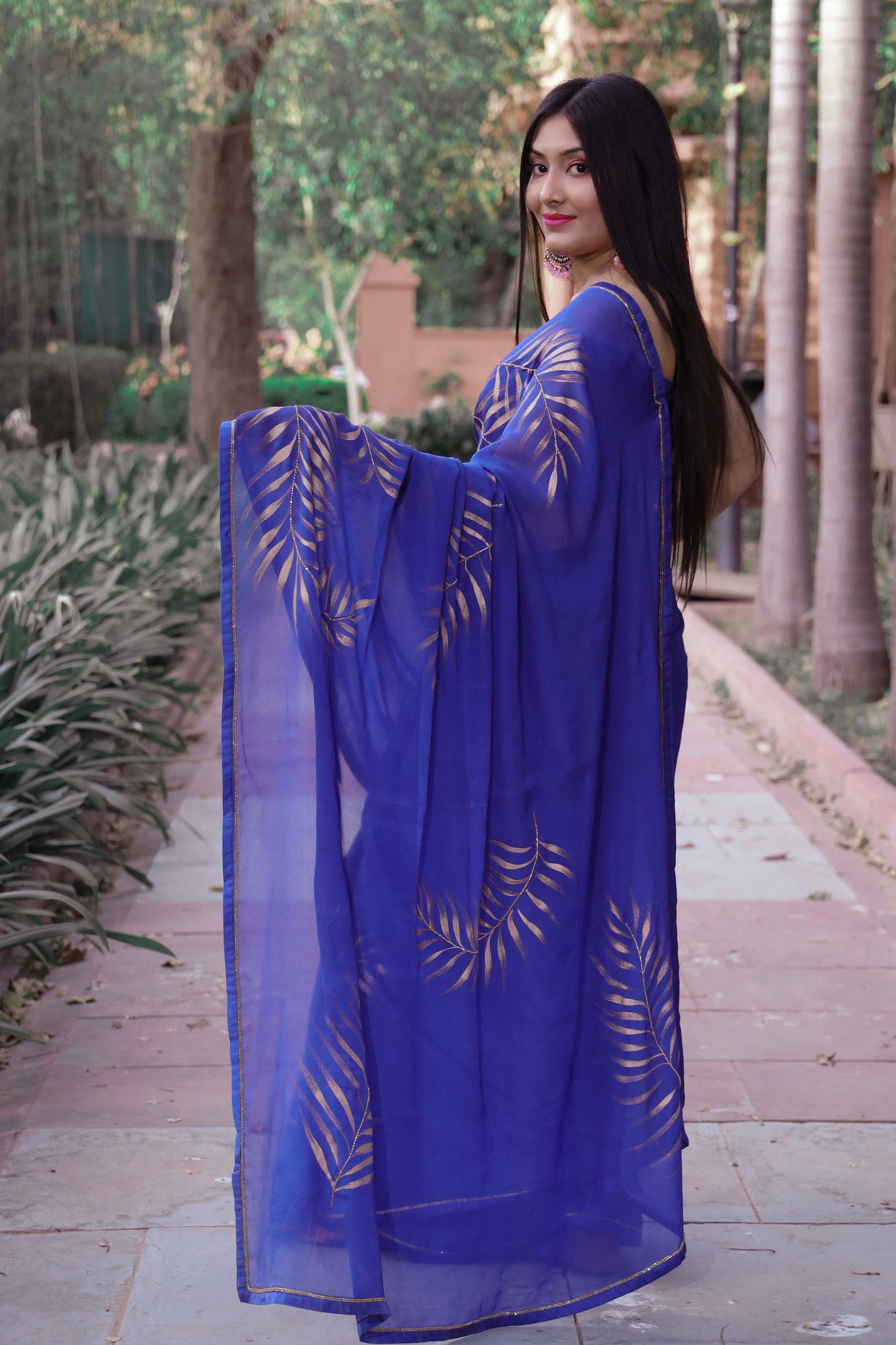 Elegant royal blue chinon chiffon silk saree with hand-painted golden palm leaves and cut beads embroidery. A stunning saree for a stylish, simple saree look. Perfect for weddings and special occasions