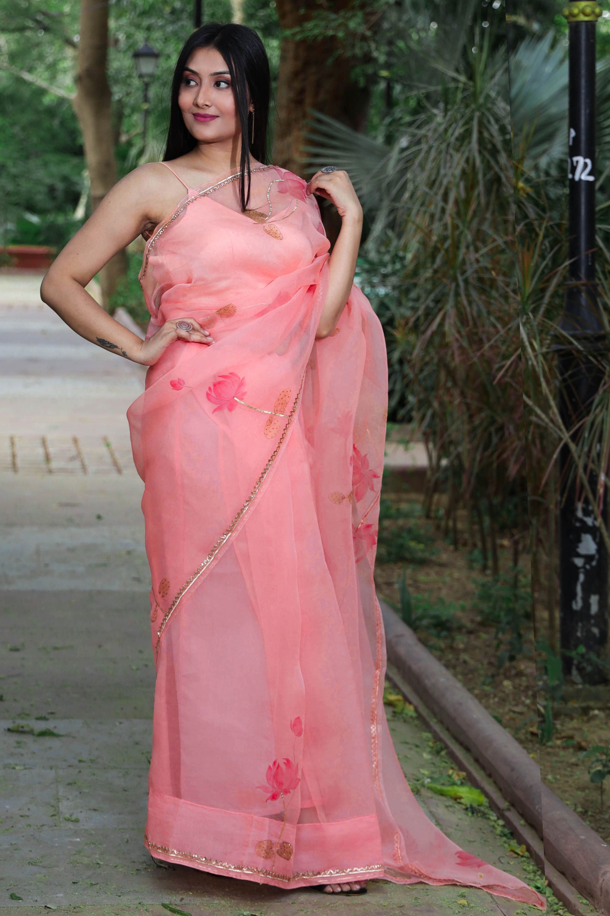 Hand painted peach color organza silk lotus saree enhanced with metal gota embroidery.