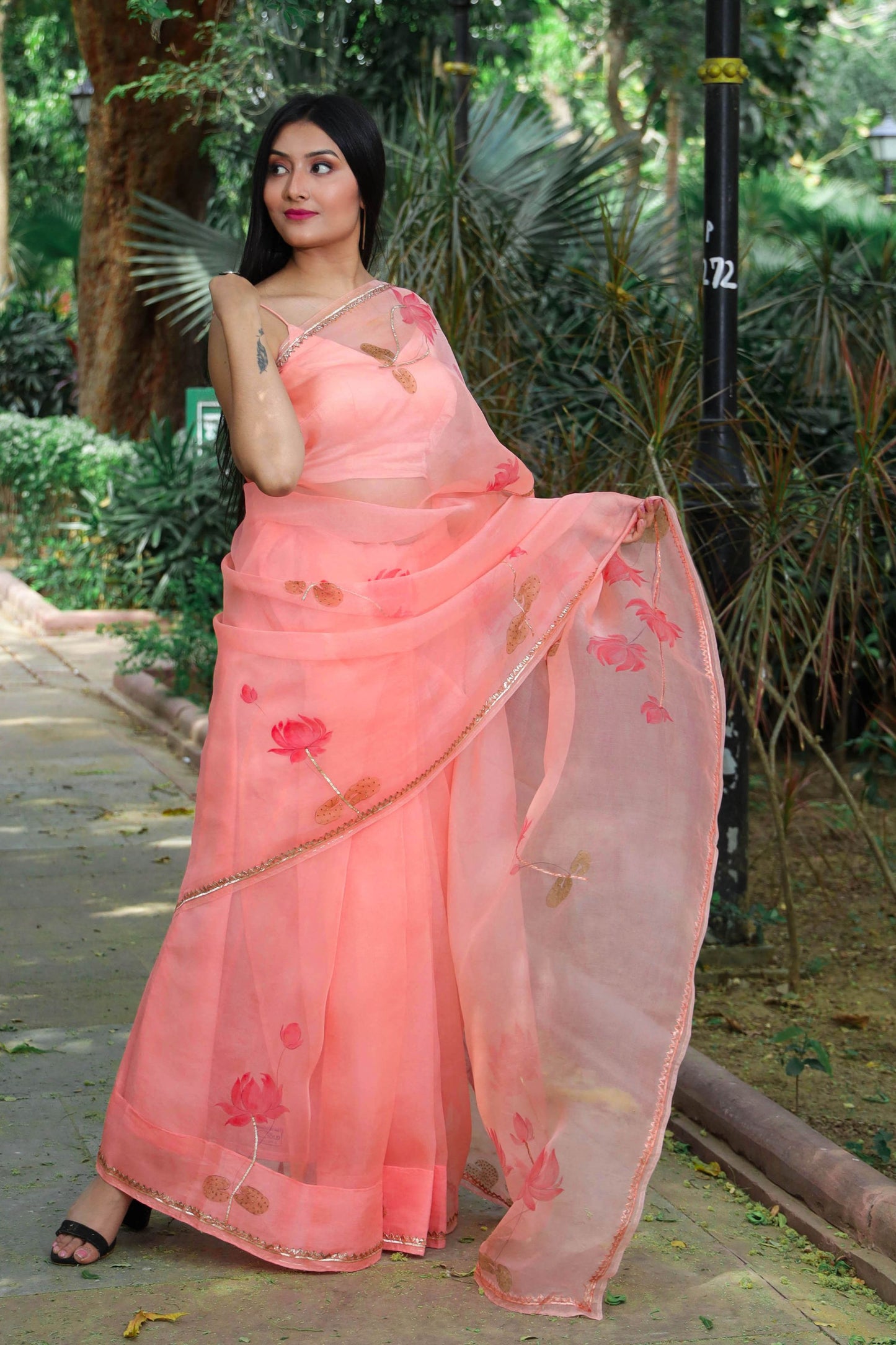 Hand painted peach color organza silk lotus saree enhanced with metal gota embroidery.