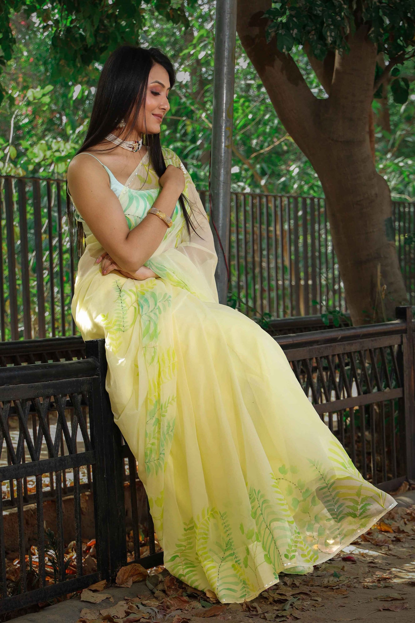 Elegant royal blue chiffon saree adorned with hand-painted green fern leaves and enhanced with glass beads and sequin embroidery. A chic and stylish chiffon saree with a transparent look