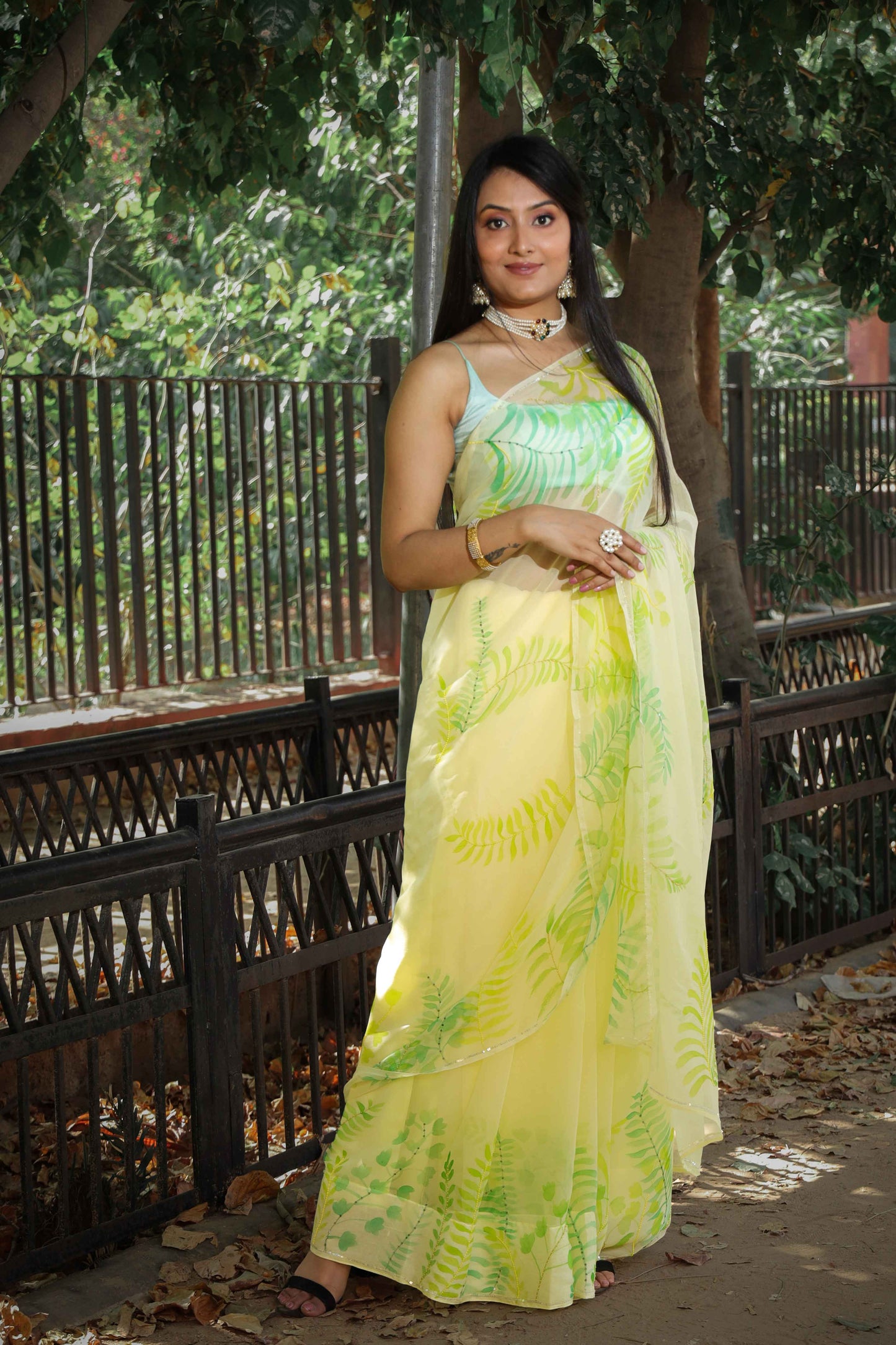 Elegant royal blue chiffon saree adorned with hand-painted green fern leaves and enhanced with glass beads and sequin embroidery. A chic and stylish chiffon saree with a transparent look
