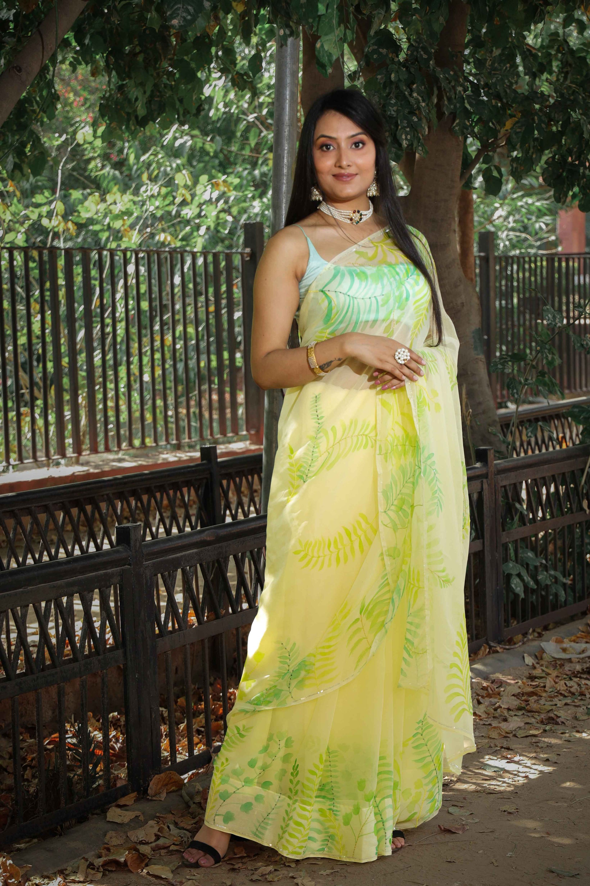 Elegant royal blue chiffon saree adorned with hand-painted green fern leaves and enhanced with glass beads and sequin embroidery. A chic and stylish chiffon saree with a transparent look