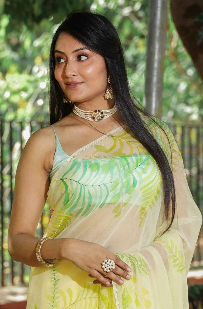 Elegant royal blue chiffon saree adorned with hand-painted green fern leaves and enhanced with glass beads and sequin embroidery. A chic and stylish chiffon saree with a transparent look