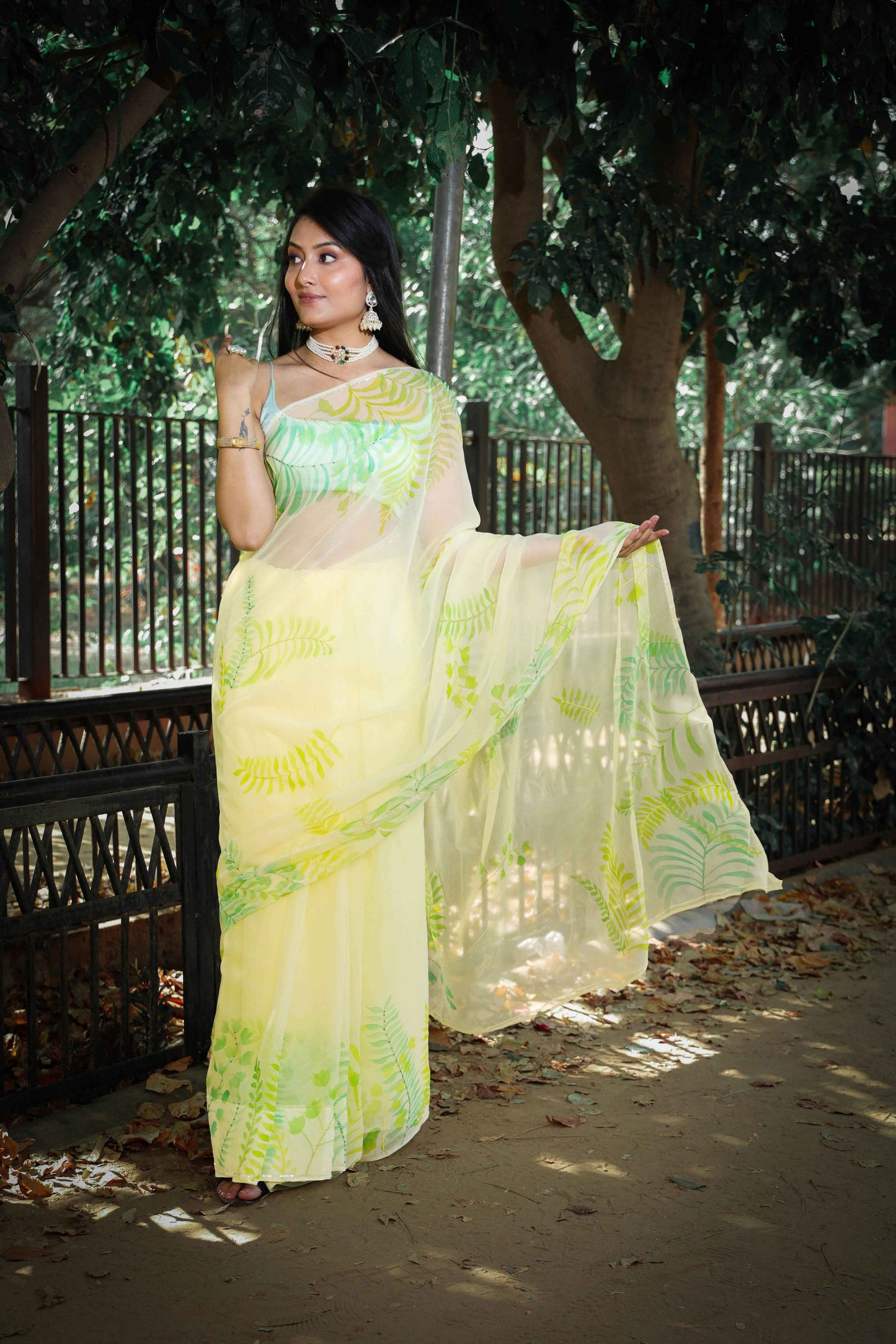 Elegant royal blue chiffon saree adorned with hand-painted green fern leaves and enhanced with glass beads and sequin embroidery. A chic and stylish chiffon saree with a transparent look