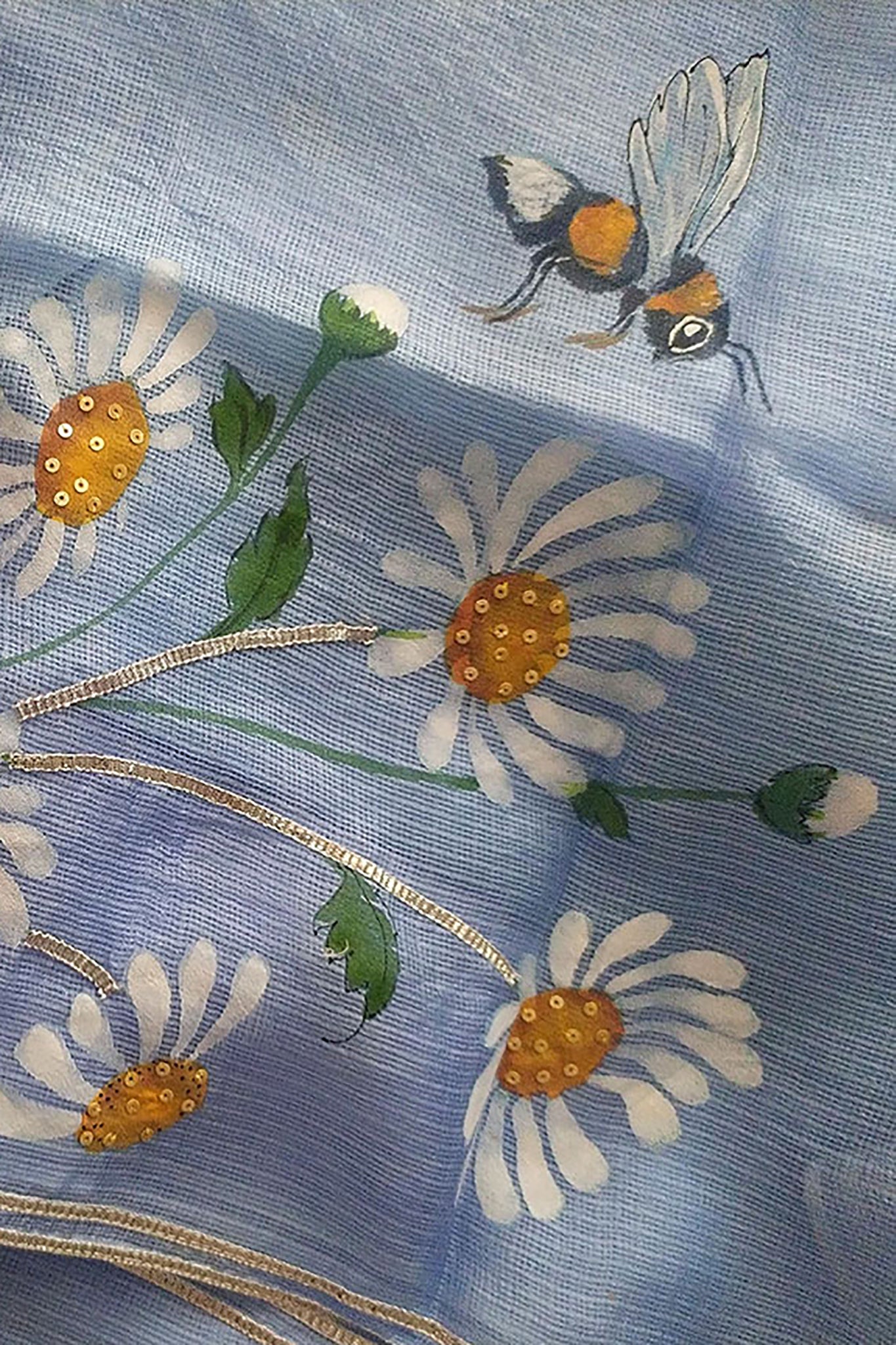 Exquisite hand-painted Kota Doria Silk Saree adorned with delicate white daisies, intricately enhanced with sequin and gota hand embroidery. A masterpiece of hand painting on saree, showcasing the elegance of pure Kota silk. This Kota saree is a timeless beauty that epitomizes artistry and grace.