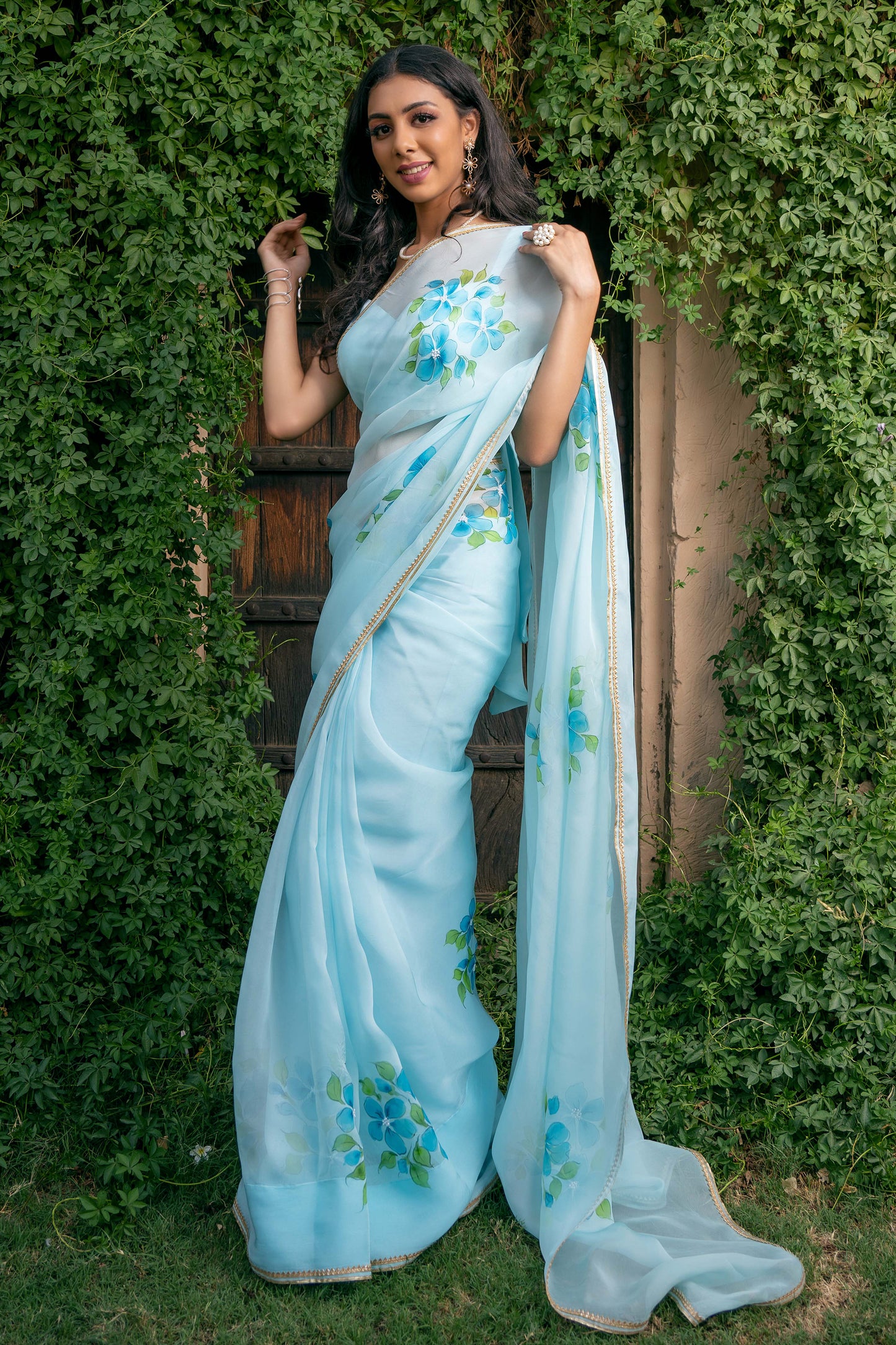 Capture the essence of elegance with this light turquoise Plumeria hand-painted organza saree from our latest collection. This handwork saree is the most popular and trending saree designs. Complete with a stitched blouse, this fancy organza saree is a testament to timeless beauty, reminiscent of Bollywood and Sabyasachi styles. Elevate your wardrobe with this beautiful handloom saree, the epitome of sophistication and grace, now available in our latest design series