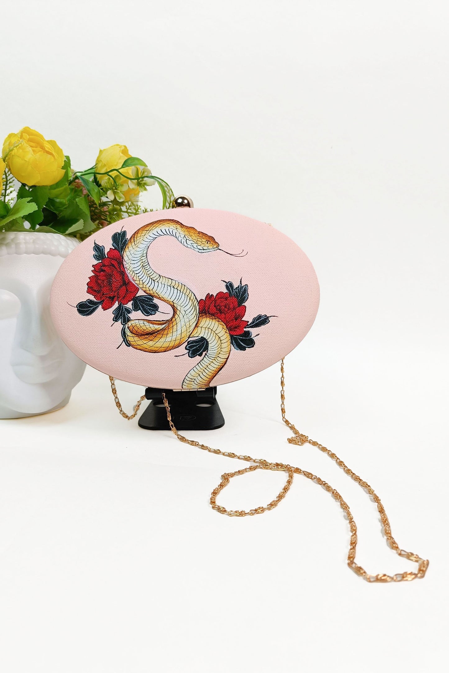 Hand-Painted Clutch with Python sitting on Red Rose Flowers Design - Customized Canvas Bag with Sling. Unique Hand-Painted Purse for Evening Events. Explore our Hand-Painted Handbags and Customized Ladies Purse with Name Options. Perfect Bag Design Online. Ideal for a Personalized and Stylish Look. Get Your Painted Designer Bag Today