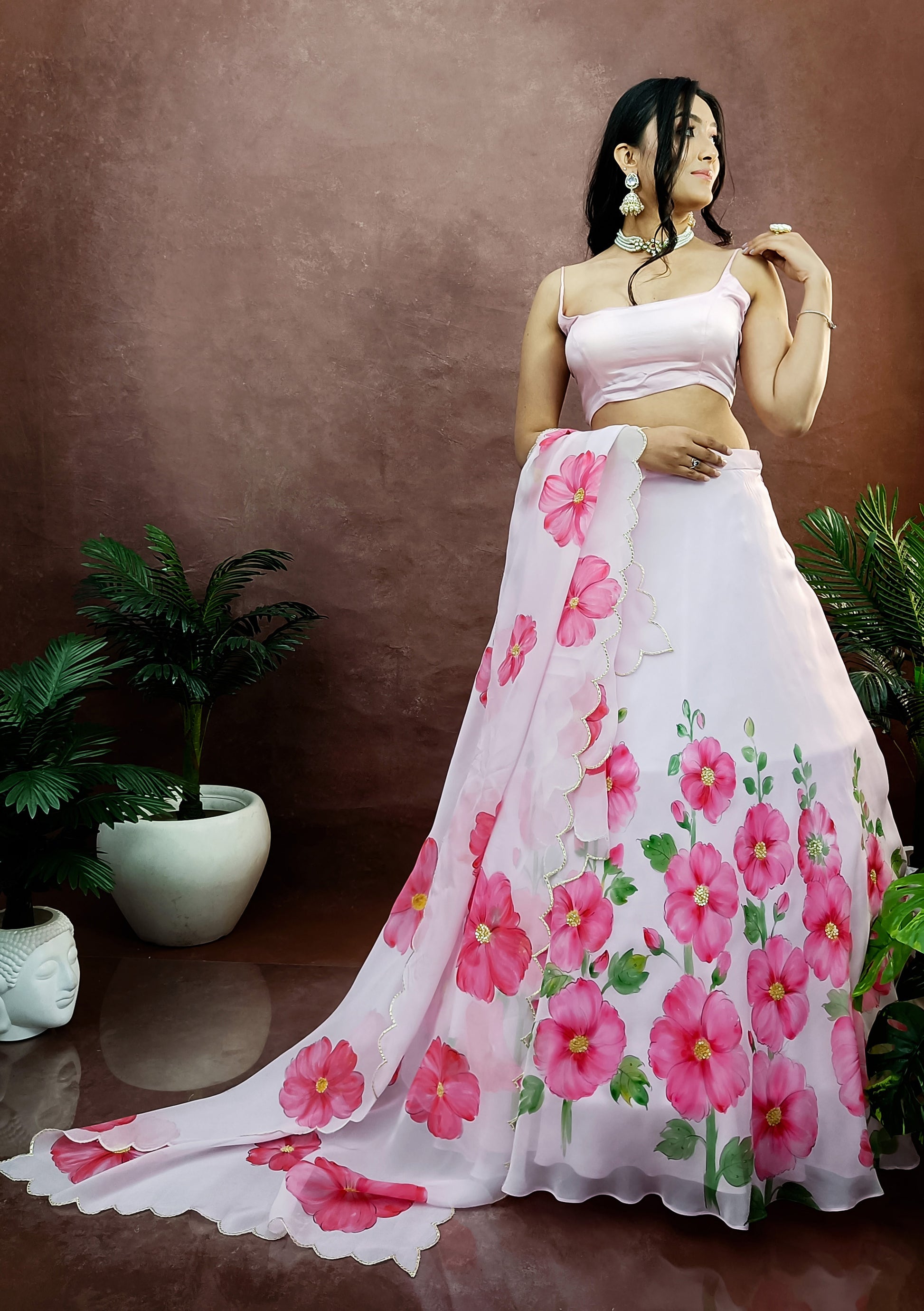 Hand painted hollyhocks on baby pink organza lehenga paired with an organza  painted dupatta enhanced with sequin embroidery and gota scalloping.