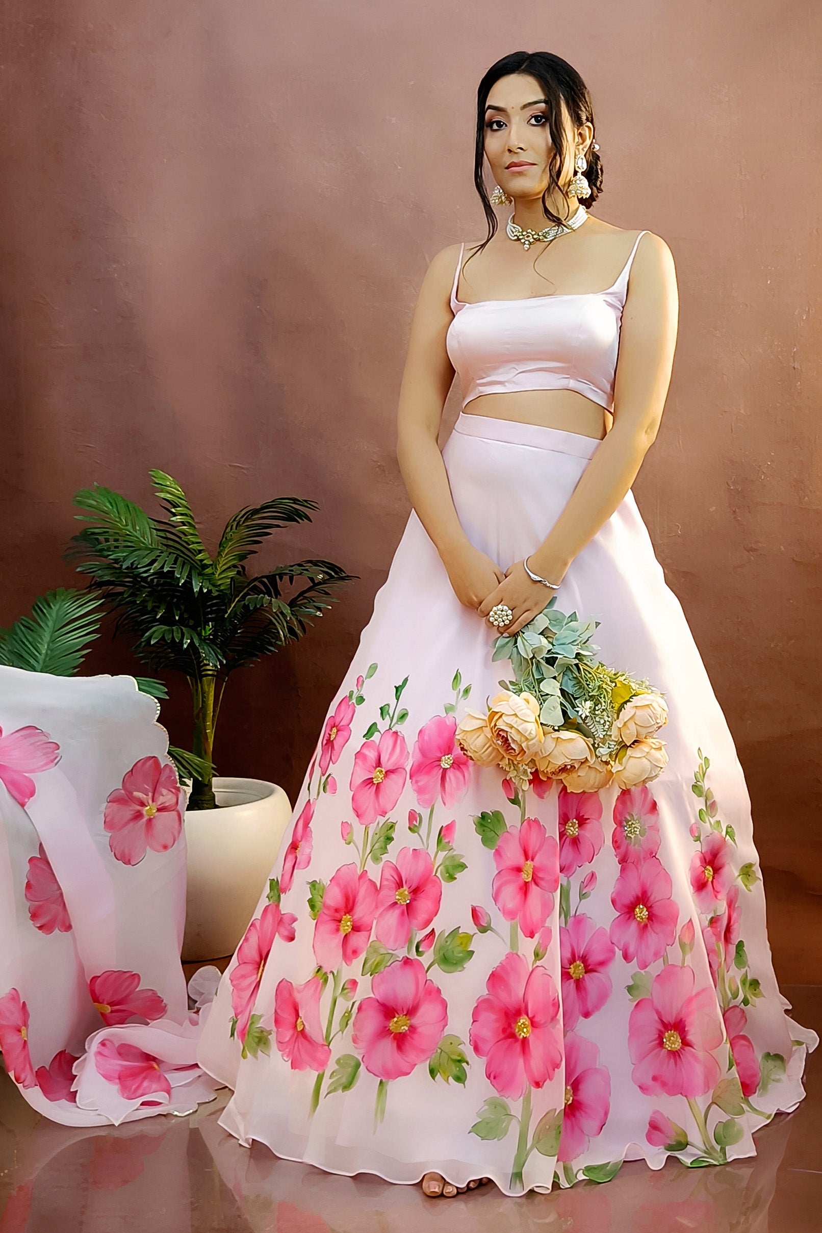 Hand painted hollyhocks on baby pink organza lehenga paired with an organza  painted dupatta enhanced with sequin embroidery and gota scalloping.
