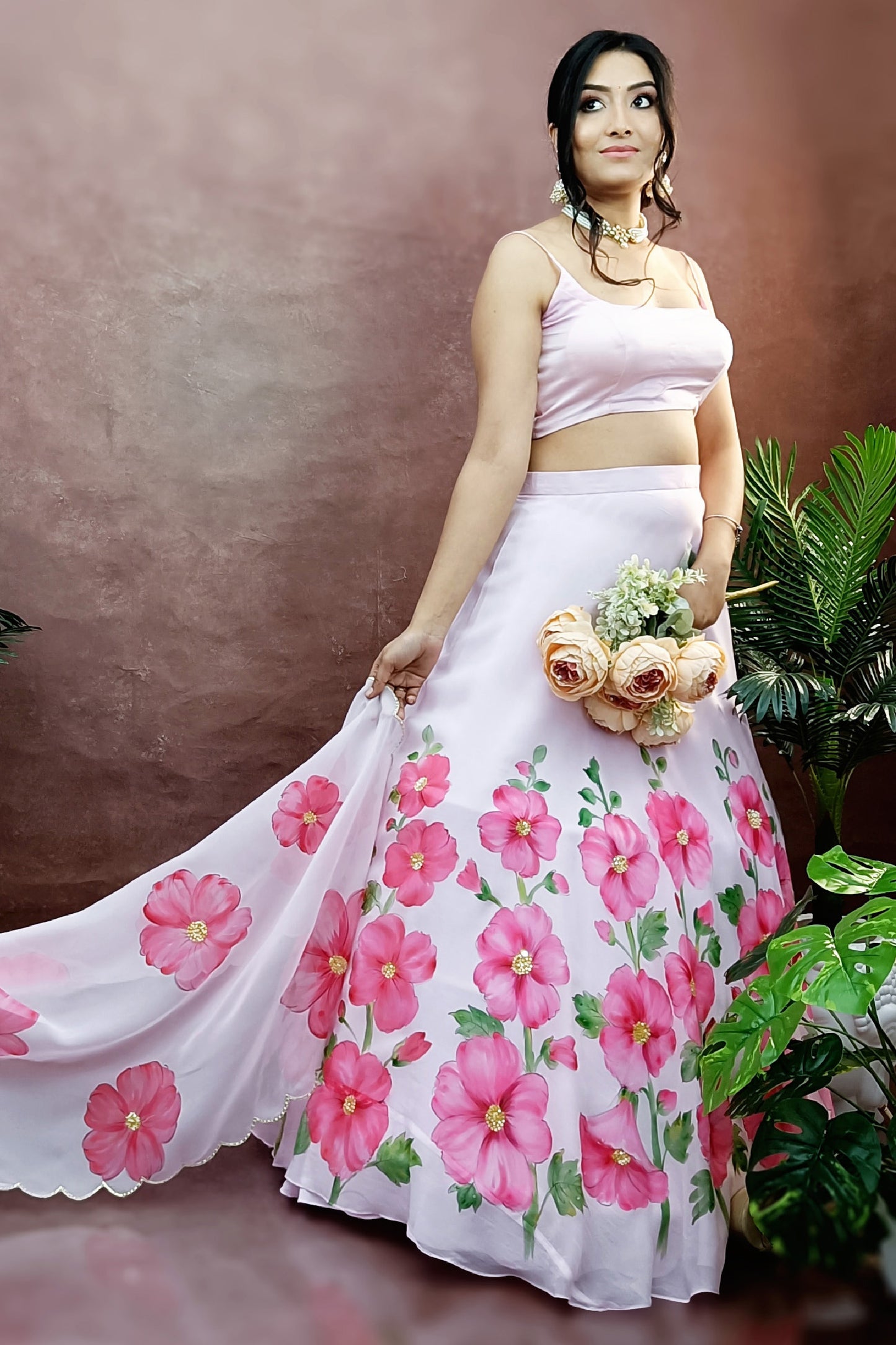 Hand painted hollyhocks on baby pink organza lehenga paired with an organza  painted dupatta enhanced with sequin embroidery and gota scalloping.