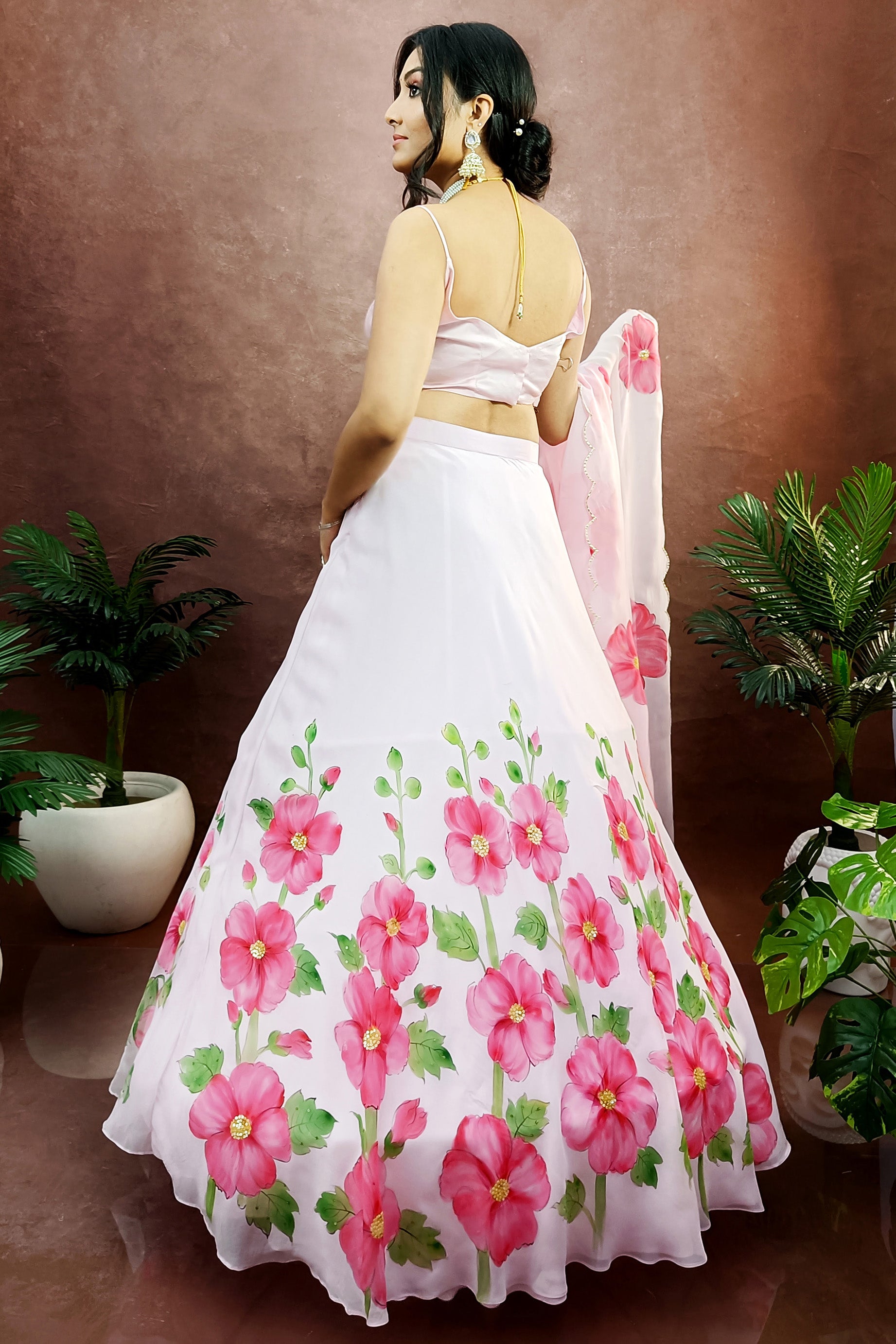 Hand painted hollyhocks on baby pink organza lehenga paired with an organza  painted dupatta enhanced with sequin embroidery and gota scalloping.
