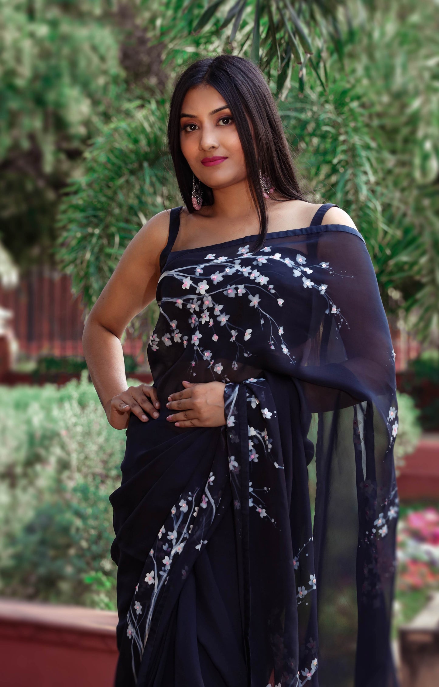 Elegant black organza saree with hand-painted floral design, perfect for parties and special occasions. Features a stunning black saree blouse design and intricate hand painting on saree. This organza saree offers a chic and stylish look, ideal for women who appreciate black saree in silk. A fashionable choice for black saree party wear