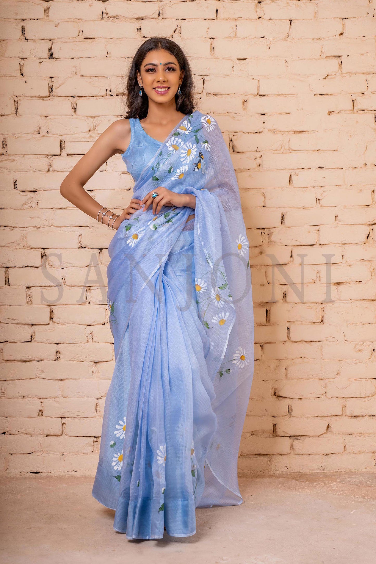 Exquisite hand-painted Kota Doria Silk Saree adorned with delicate white daisies, intricately enhanced with sequin and gota hand embroidery. A masterpiece of hand painting on saree, showcasing the elegance of pure Kota silk. This Kota saree is a timeless beauty that epitomizes artistry and grace.