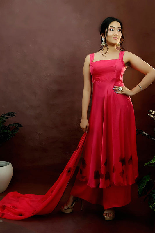 Girl wearing a red colour sleeveless anarkali suit enhanced with hand painted black poppy flowers adorned with delicate bead work., paired with organza handpainted dupatta and a flared palazzo.
