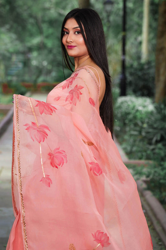 Hand painted peach color organza silk lotus saree enhanced with metal gota embroidery.