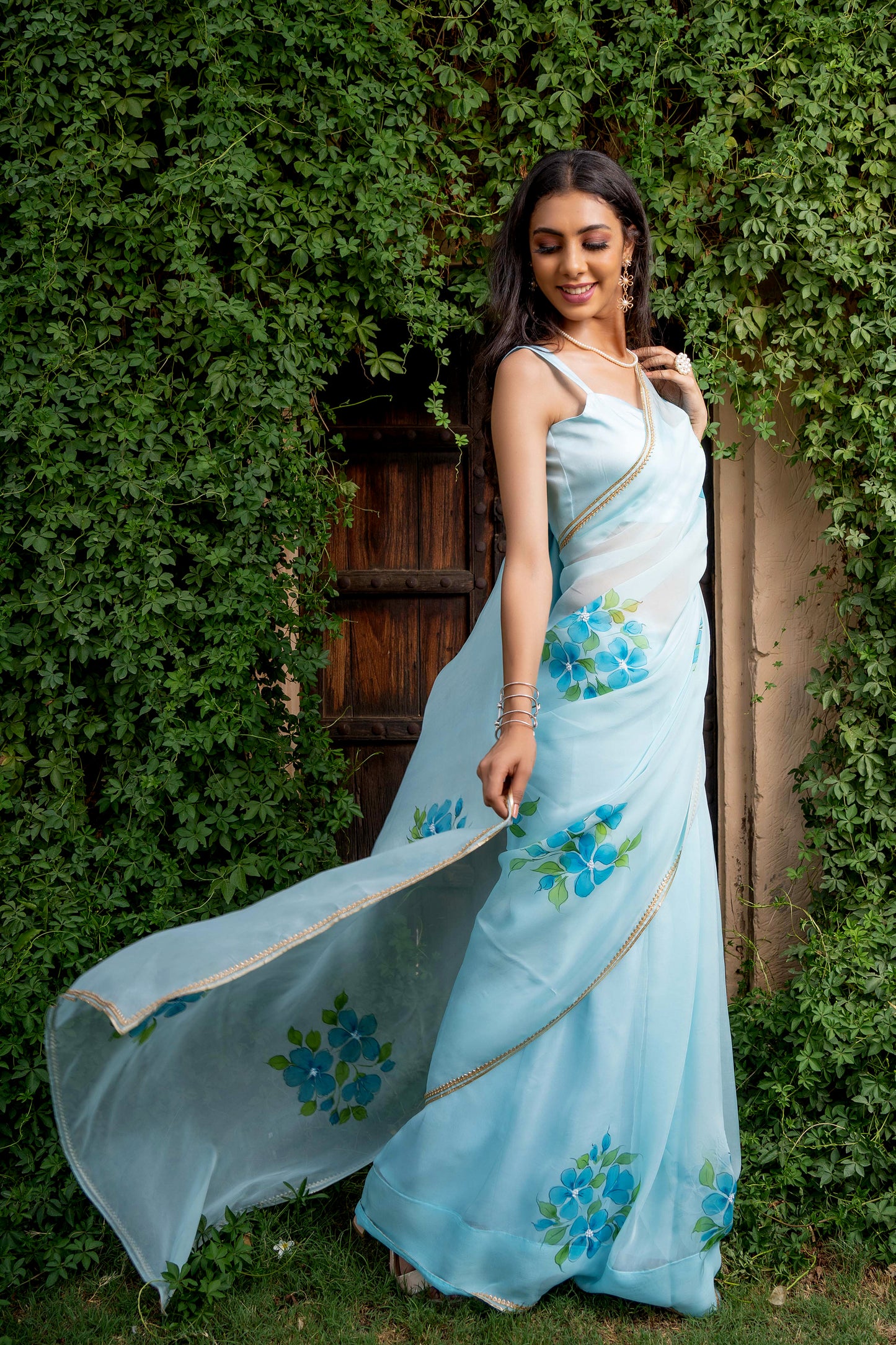 Capture the essence of elegance with this light turquoise Plumeria hand-painted organza saree from our latest collection. This handwork saree is the most popular and trending saree designs. Complete with a stitched blouse, this fancy organza saree is a testament to timeless beauty, reminiscent of Bollywood and Sabyasachi styles. Elevate your wardrobe with this beautiful handloom saree, the epitome of sophistication and grace, now available in our latest design series