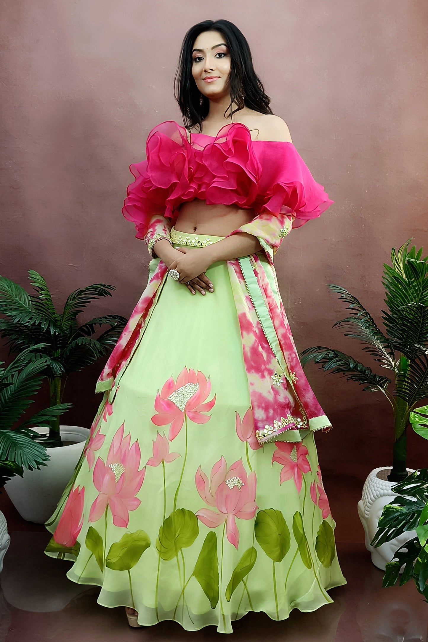 Hand painted lotus lehenga on green organza  paired with tie and die dupatta enhanced with mirror embroidery and a ruffel blouse.